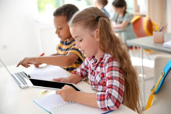 Niedliche Kleine Kinder Mit Gadgets Sitzen Schreibtisch Klassenzimmer Grundschule — Stockfoto