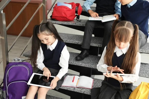 Little children in stylish school uniform on stairs indoors