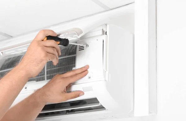 Male Technician Fixing Modern Air Conditioner Indoors — Stock Photo, Image