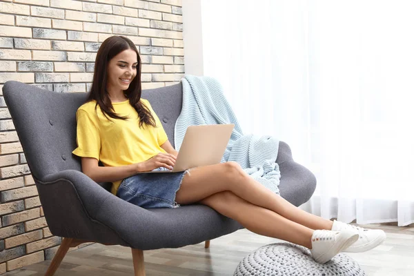 自宅のソファーに座っている現代のラップトップを持つ若い女性 — ストック写真