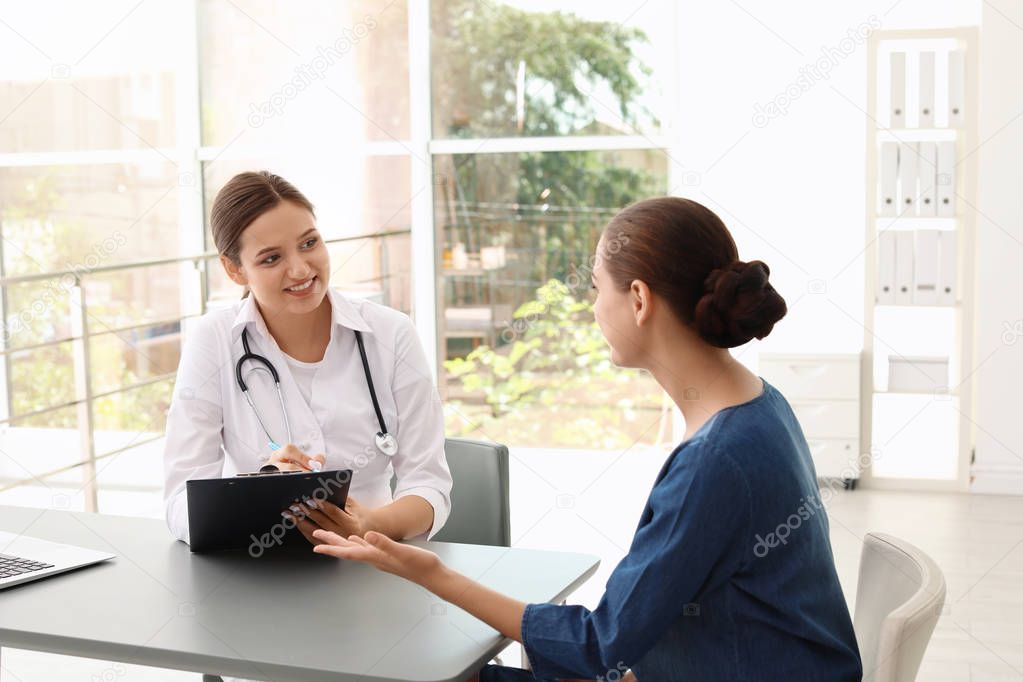 Young doctor listening to patient's complaints in hospital