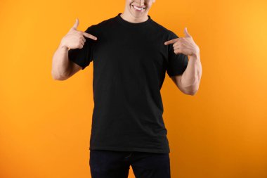Renk arka plan üzerinde siyah t-shirt genç adam. Mockup tasarım için