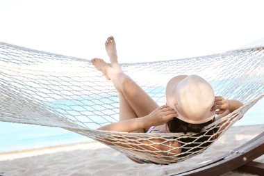 Genç kadın seaside, hamakta dinleniyor. Yaz tatili