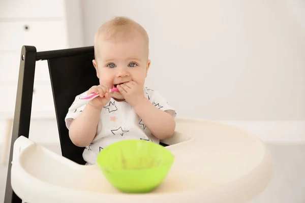 かわいい赤ちゃんが自宅で高い椅子で食べる — ストック写真