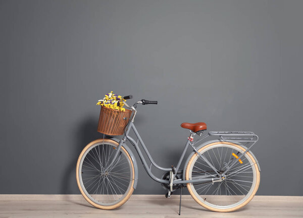 Retro bicycle with wicker basket near color wall