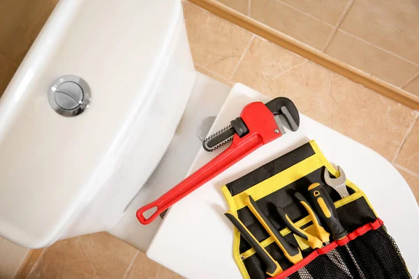 Different plumber\'s tools on toilet seat lid indoors