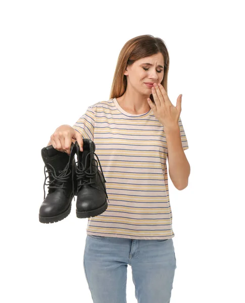Woman feeling bad smell from shoes on white background. Air freshener