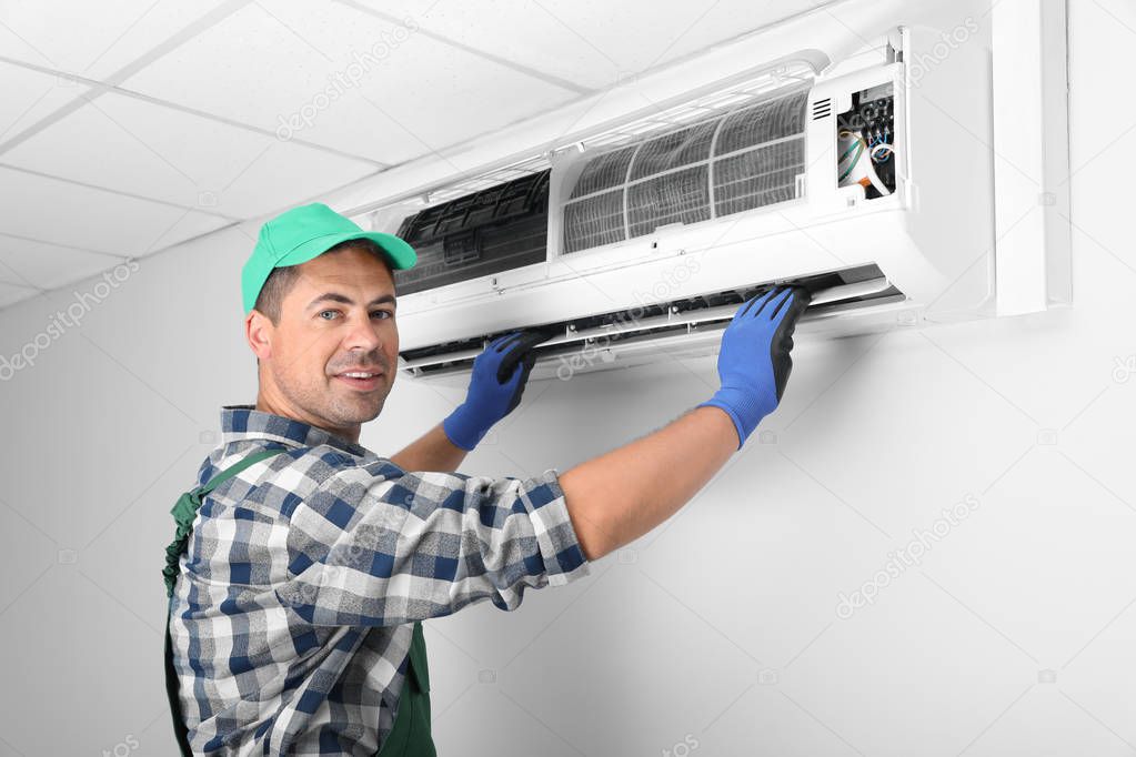 Male technician installing air conditioner indoors