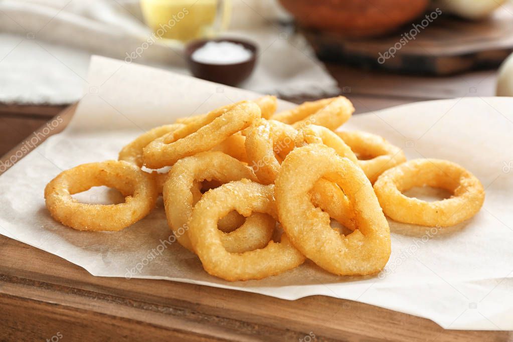 Tasty fried onion rings on wooden table