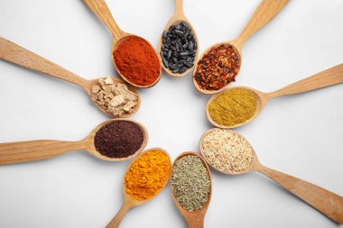 Beyaz arka planda ahşap kaşıklarda farklı aromatik baharatlar içeren kompozisyon