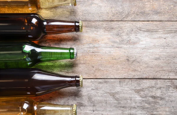 Bottles with different types of beer on wooden background