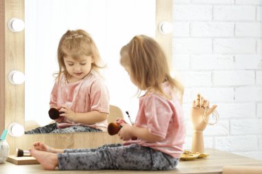 Sevimli küçük kız soyunma odasında kozmetik ile oynarken