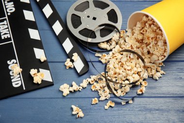Patlamış mısır, film makaraları ve ahşap arka plan üzerinde Klaket ile kompozisyon