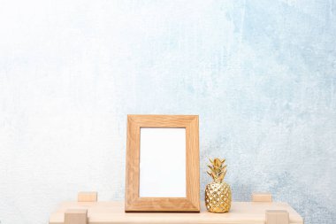 Boş çerçeve ve dekoratif ananas ışık duvarının yakınında masada bul. Tasarım için alay