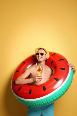 Shirtless man with inflatable ring and cocktail on color background clipart