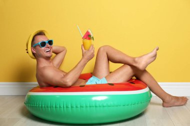 Gömleksiz adam şişme yüzük ve kokteyl bardak renk duvarının yakınında katta