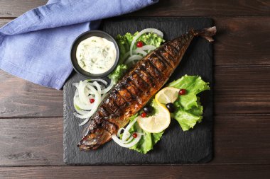 Kayrak plaka lezzetli ızgara balık ve ahşap masa, üstten görünüm sosu ile
