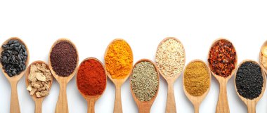Beyaz arka planda ahşap kaşıklarda farklı aromatik baharatlar içeren kompozisyon