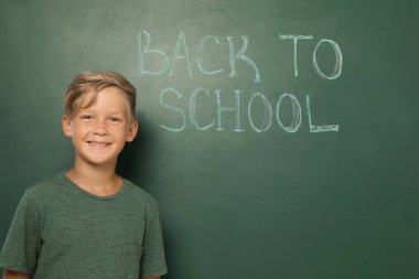 Küçük çocuğun okul için metinle kara tahta yanında