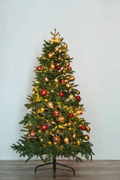 美丽的圣诞树与童话灯和节日装饰附近白色墙壁 — 图库照片