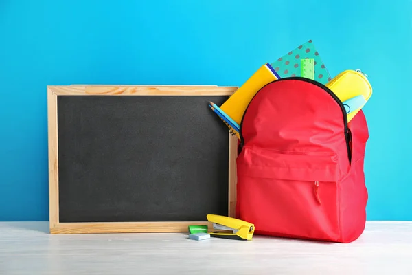 Kleine Tafel Und Rucksack Mit Verschiedenen Schulsachen Auf Dem Tisch — Stockfoto