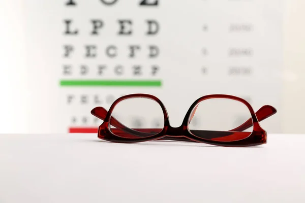 Brille Mit Korrekturgläsern Auf Tisch Gegen Augentafel — Stockfoto