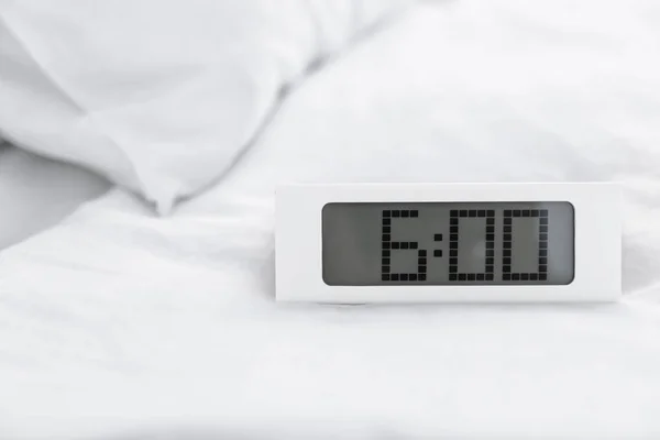 Digital alarm clock on bed. Time to wake up