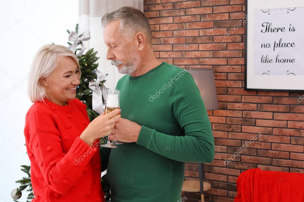 Mature couple with glasses of champagne at home. Christmas celebration
