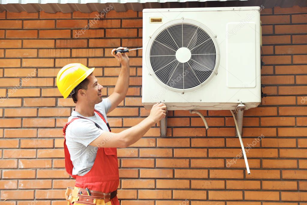 Male technician fixing air conditioner outdoors