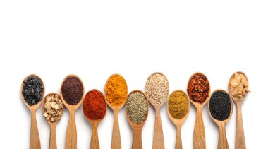 Beyaz arka planda ahşap kaşıklarda farklı aromatik baharatlar içeren kompozisyon