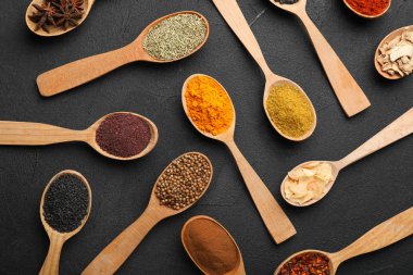 Koyu arka plan üzerinde tahta kaşıklar içinde farklı Aromatik baharatlar ile kompozisyon