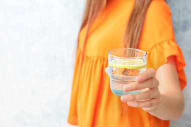 Renk arka planda, closeup bardak limonlu su tutan genç kadın