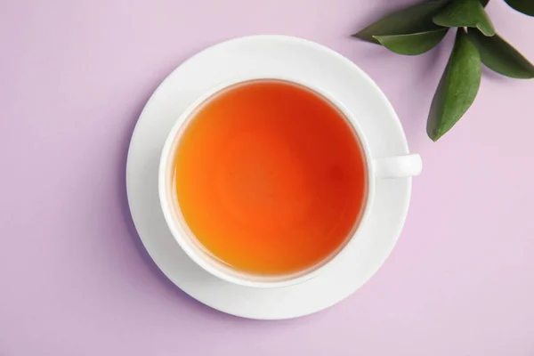 緑の葉色の背景 平面図上でおいしい紅茶のカップ — ストック写真