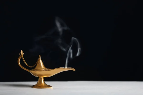 Aladdin lamp of wishes on table against black background