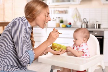 Kadın çocuğunu sandalyesi kapalı besleme. Sağlıklı bebek maması