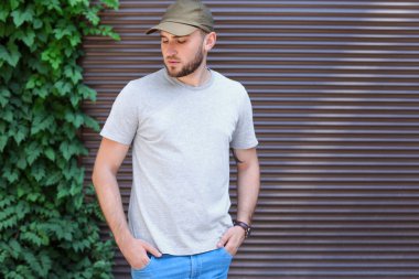 Sokakta duvarının yakınında gri t-shirt giyen genç adam. Kentsel tarzı