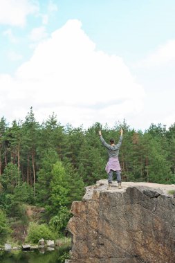 Genç adam göl ve orman yakınındaki kayaya. Kamp sezon