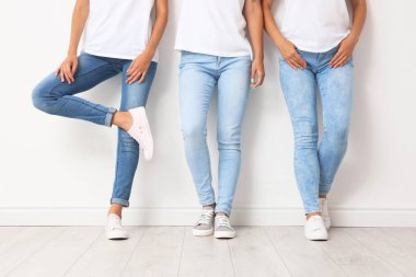 Grup Genç kadını Jeans ışık duvarının yakınında