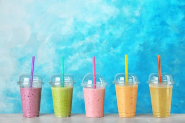 Renk arka plan karşı masada smoothies ile plastik bardak