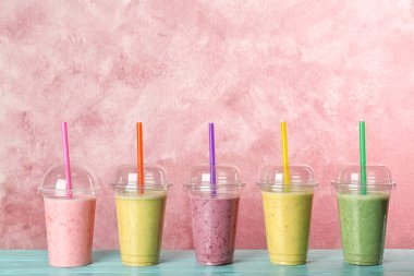 Renk arka plan karşı masada smoothies ile plastik bardak