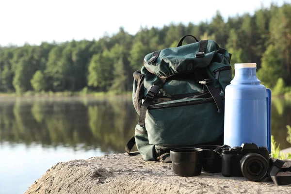 Set of camping equipment on rock near lake