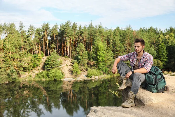 在湖和森林附近岩石的年轻人 野营季节 — 图库照片