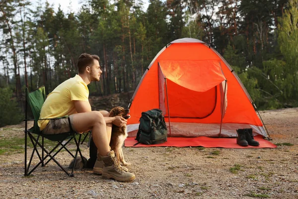 屋外のキャンプ テントの近くに犬と若い男 — ストック写真
