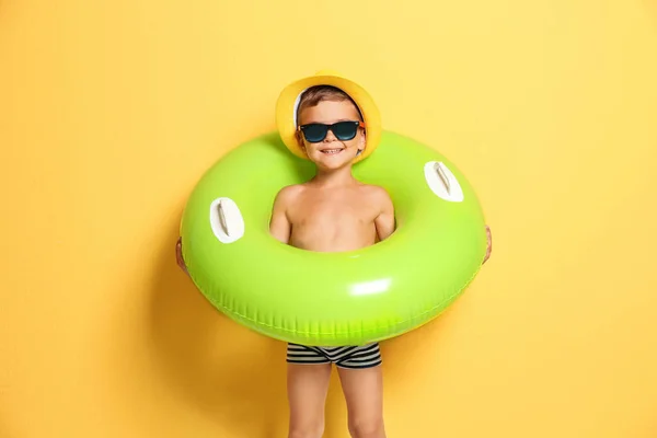 Cute little boy with inflatable ring on color background