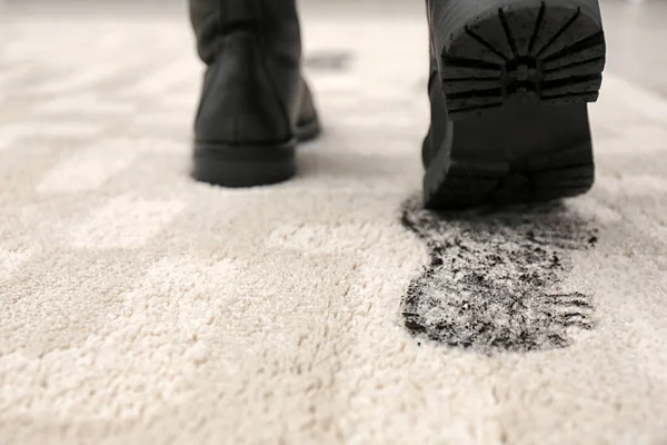 Person in dirty shoes leaving muddy footprints on carpet