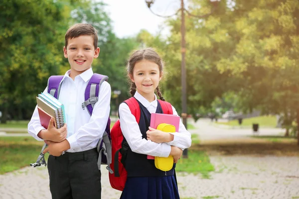 Cute little school children with stationery in park