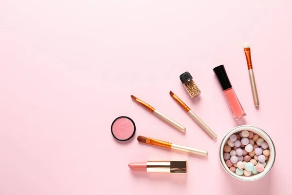 Flat lay composition with products for decorative makeup on pastel pink background