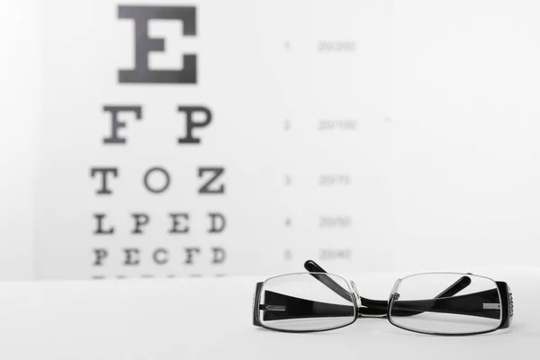 Brille Mit Korrekturgläsern Auf Tisch Gegen Augentafel — Stockfoto