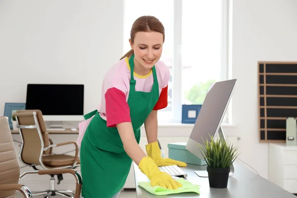 Young woman in apron and gloves cleaning office