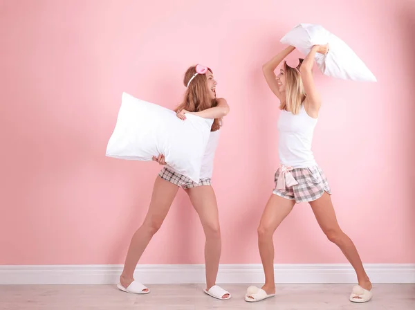 Dos Mujeres Jóvenes Teniendo Pelea Almohadas Cerca Pared Color —  Fotos de Stock